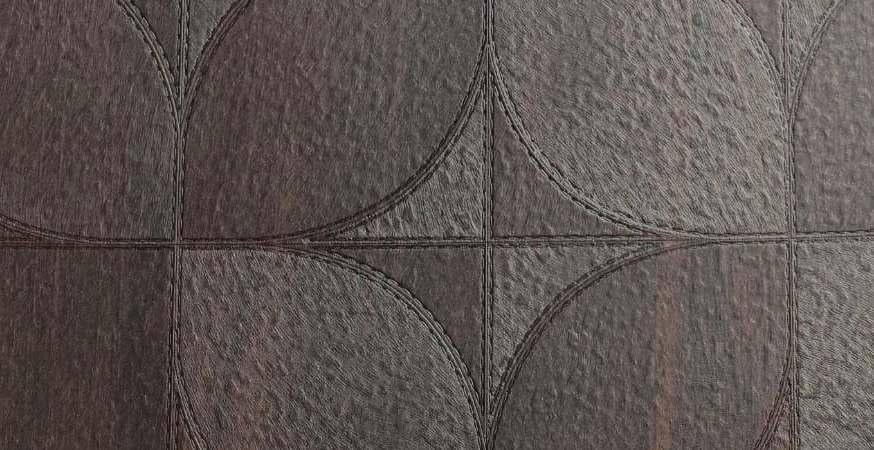 Dark brown wood laminate with textured finish and embossed floral pattern, showing wood grain details and subtle sheen.