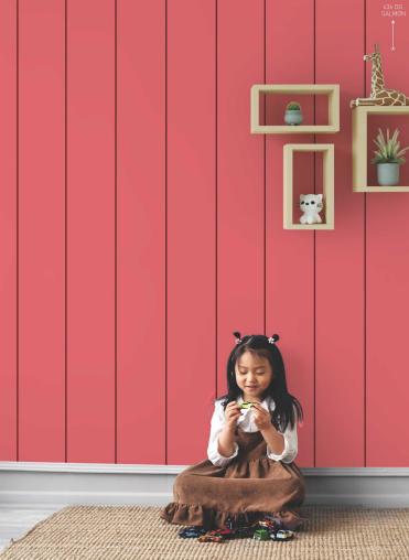 Salmon pink glossy laminate wall with vertical panels, girl sitting below decorative shelves with toys and plants