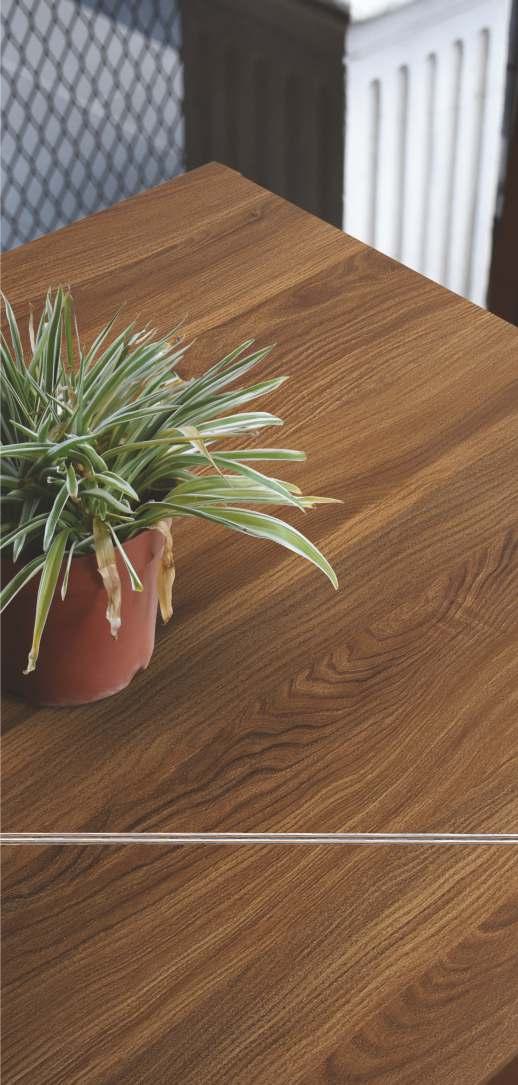 Brown wood laminate with textured finish and wood grain pattern, showing a tabletop with a potted plant
