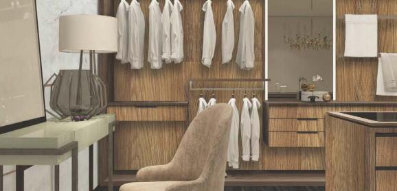 Brown wood laminate closet with textured finish, featuring hanging white clothes and a beige chair beside a glass table.