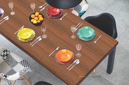 Brown wood grain laminate table top with textured finish and visible wood pattern, set with colorful dinnerware and cutlery