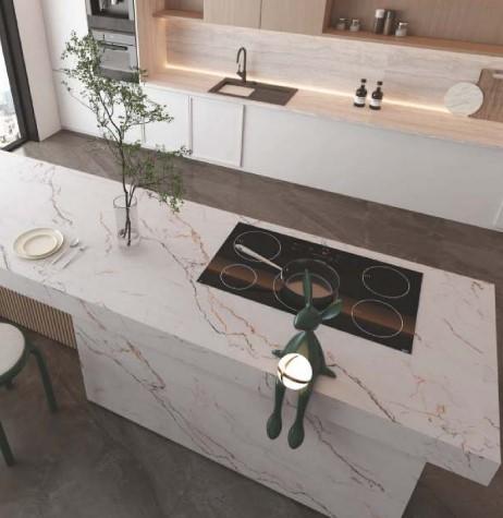White marble laminate kitchen island with textured finish and red veins, featuring cooktop and decorative plant.
