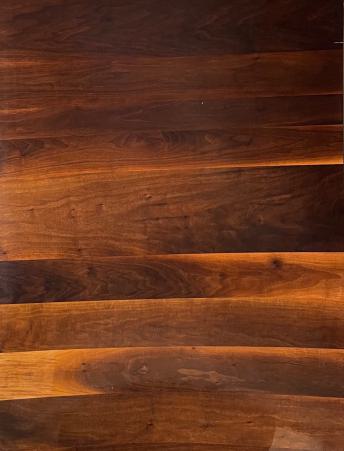 Brown natural wood veneer with horizontal grain pattern and glossy finish showing wood texture and knots.