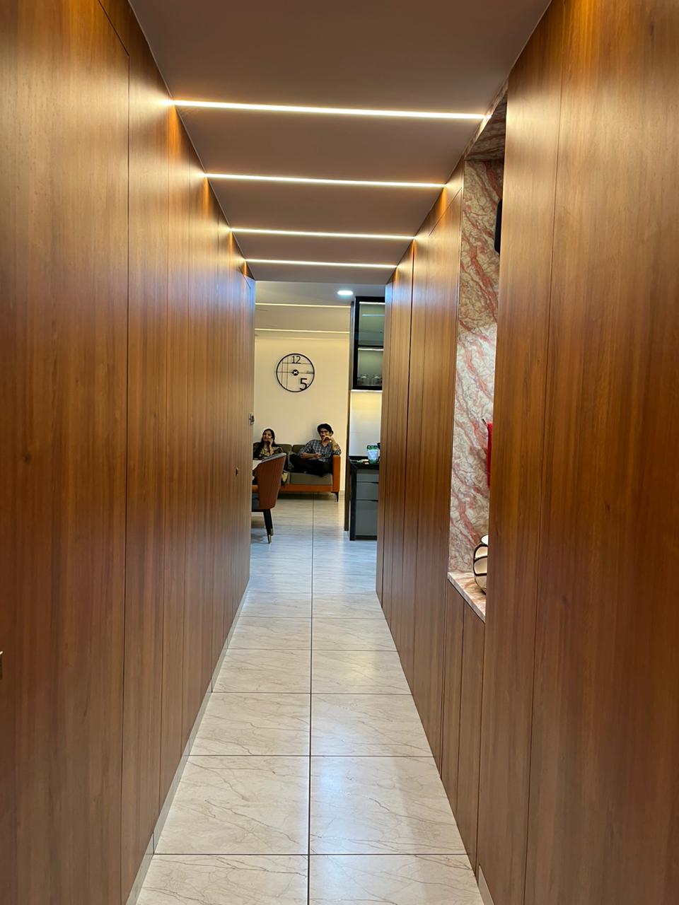Brown wood laminate wall panels with matte finish in a modern hallway with recessed lighting and marble flooring