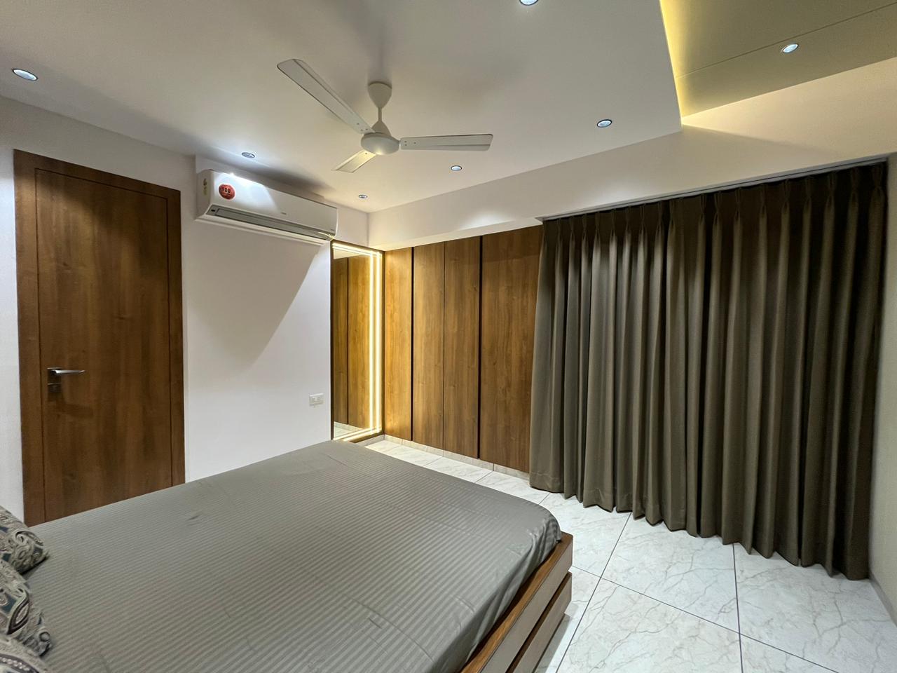 Brown wood laminate used on door and closet in a modern bedroom with gray bedding and marble flooring.