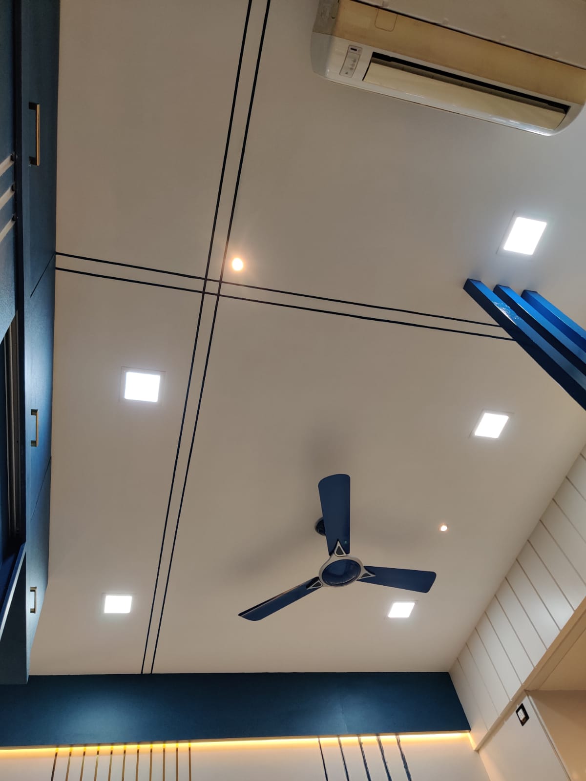 White glossy laminate ceiling with black trim and recessed lights in a modern room with dark blue accents