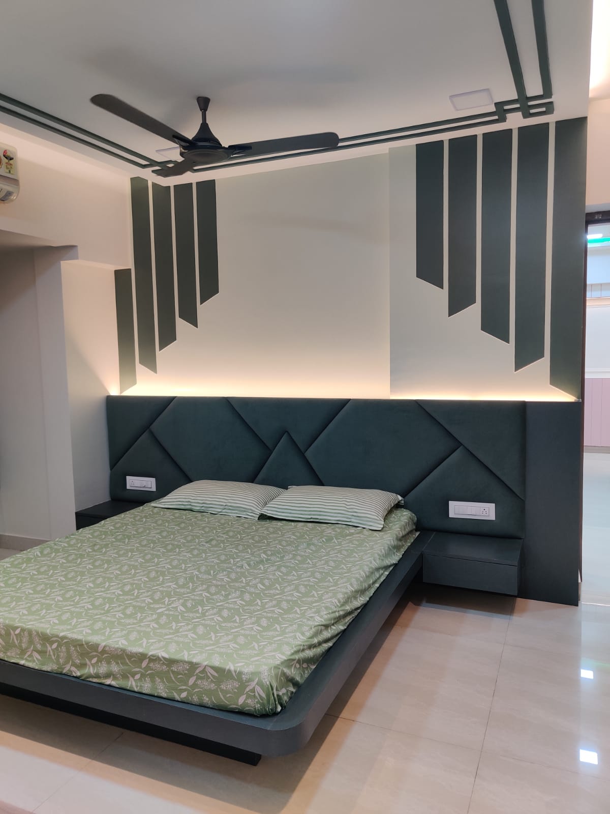 Dark green matte laminate used in bedroom decor with geometric pattern on headboard and accent wall