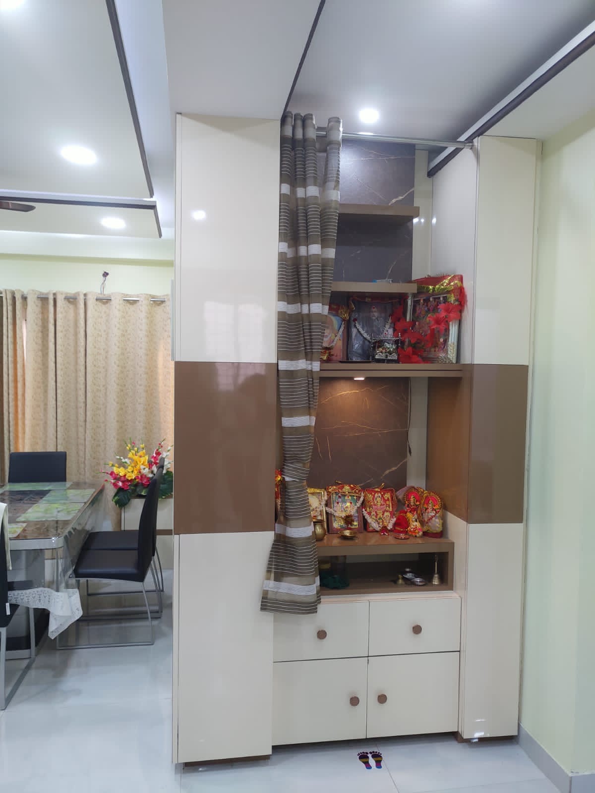 White and brown glossy laminate cabinet with shelves and drawers in a modern home interior with decorative items