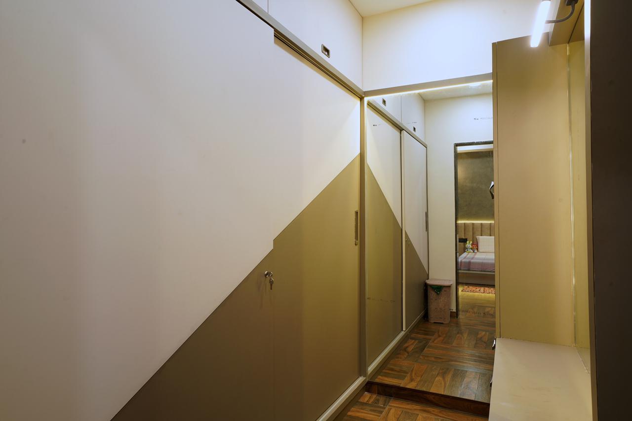 High gloss brown and white laminate wardrobe in a hallway with a bedroom visible in the background through a doorway