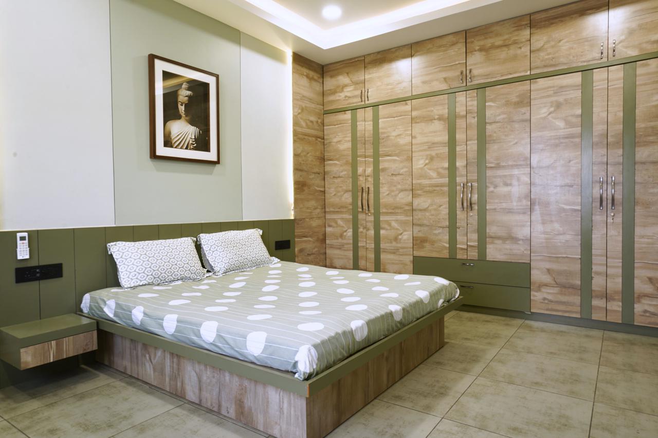 Light wood laminate wardrobe and matching bed frame in modern bedroom with green accents and patterned bedding.