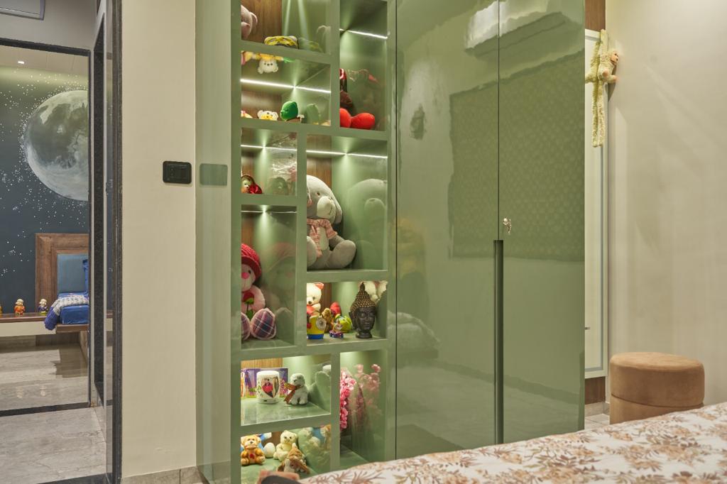 Glossy green glass cabinet with toys and decorative items, reflecting surrounding room, in a child's bedroom or play area