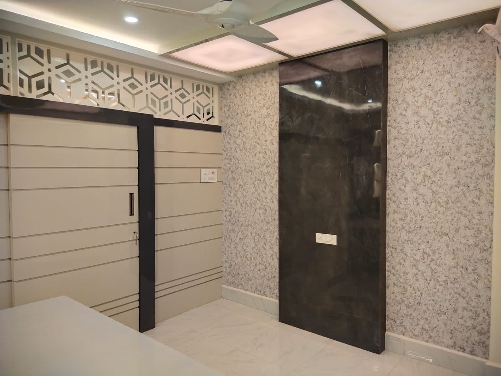 Dark grey glossy marble laminate wall with subtle veining, used in modern interior design with patterned wallpaper and white