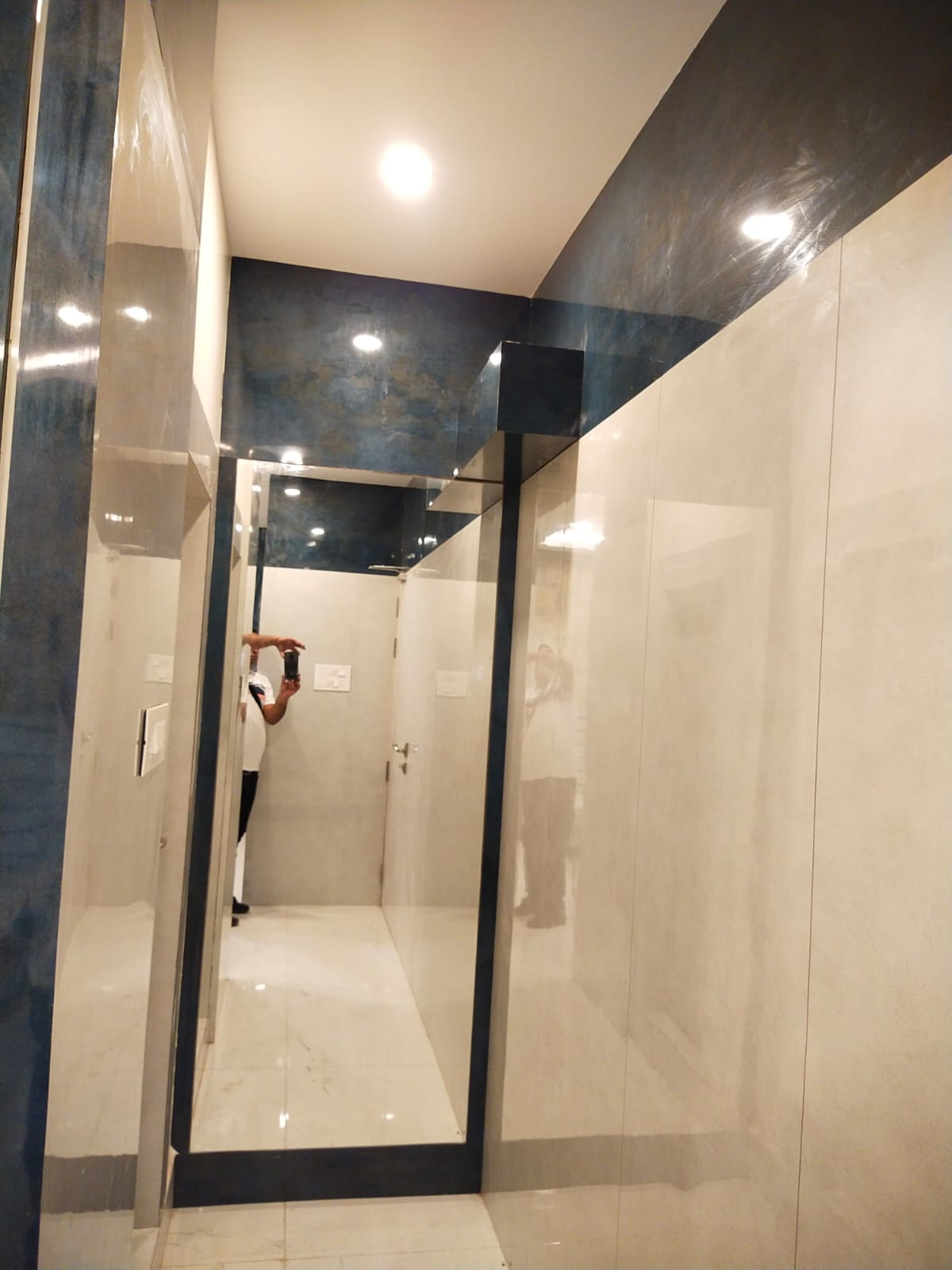 High gloss patterned laminate with reflective sheen on walls and ceiling in a modern interior setting with mirror reflection