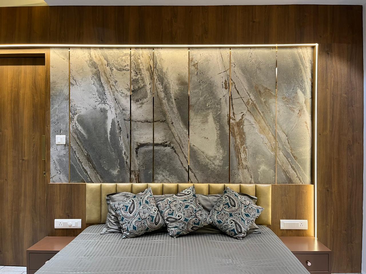 Multi-coloured marble patterned laminate wall panels behind a bed with a yellow headboard and wooden nightstands.