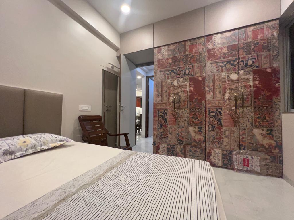 Multicolored fabric laminate closet doors with floral pattern in a bedroom with white bed and striped blanket
