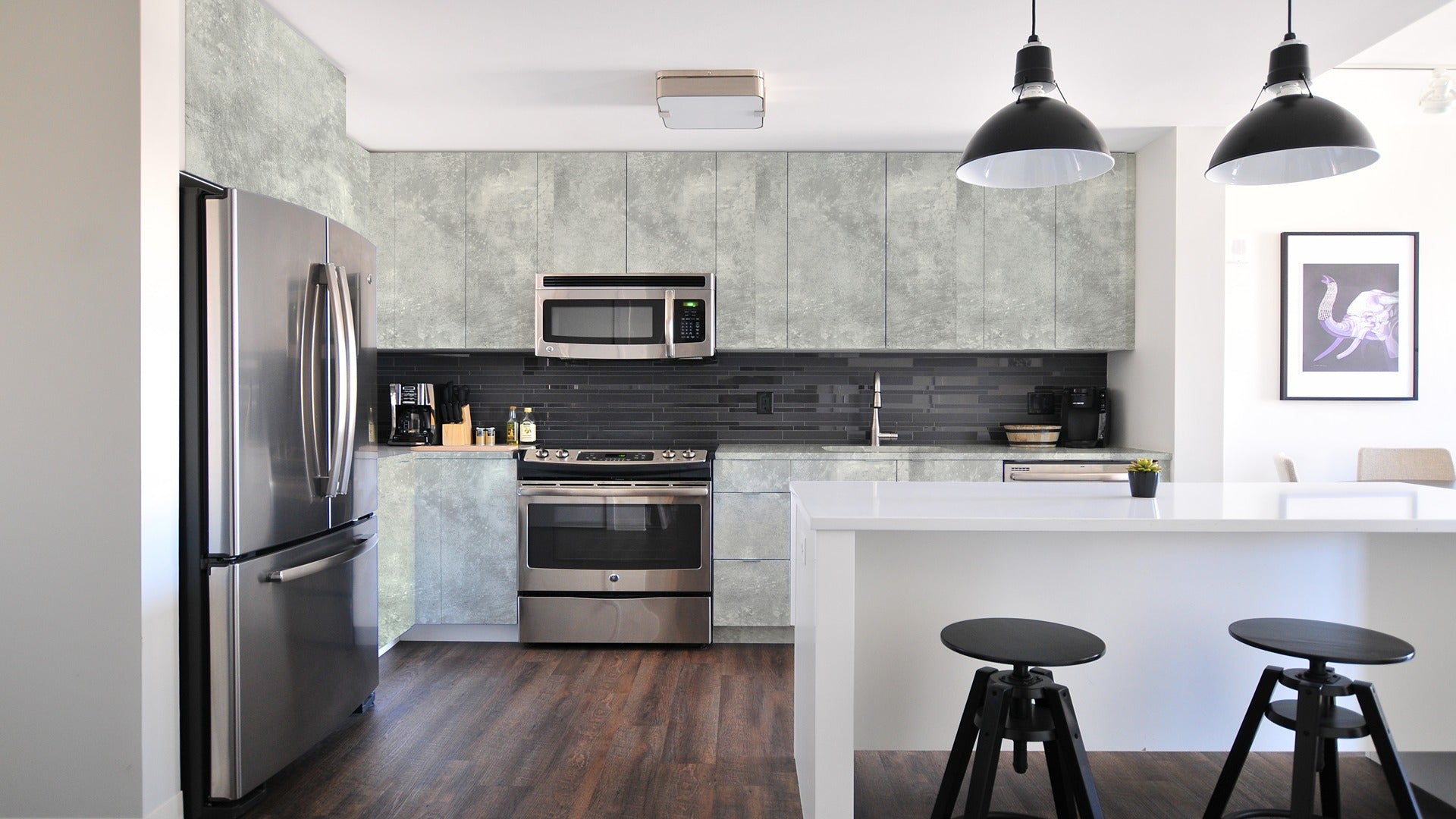 Grey marble laminate kitchen cabinets with matte finish and textured pattern on walls and upper cabinets.