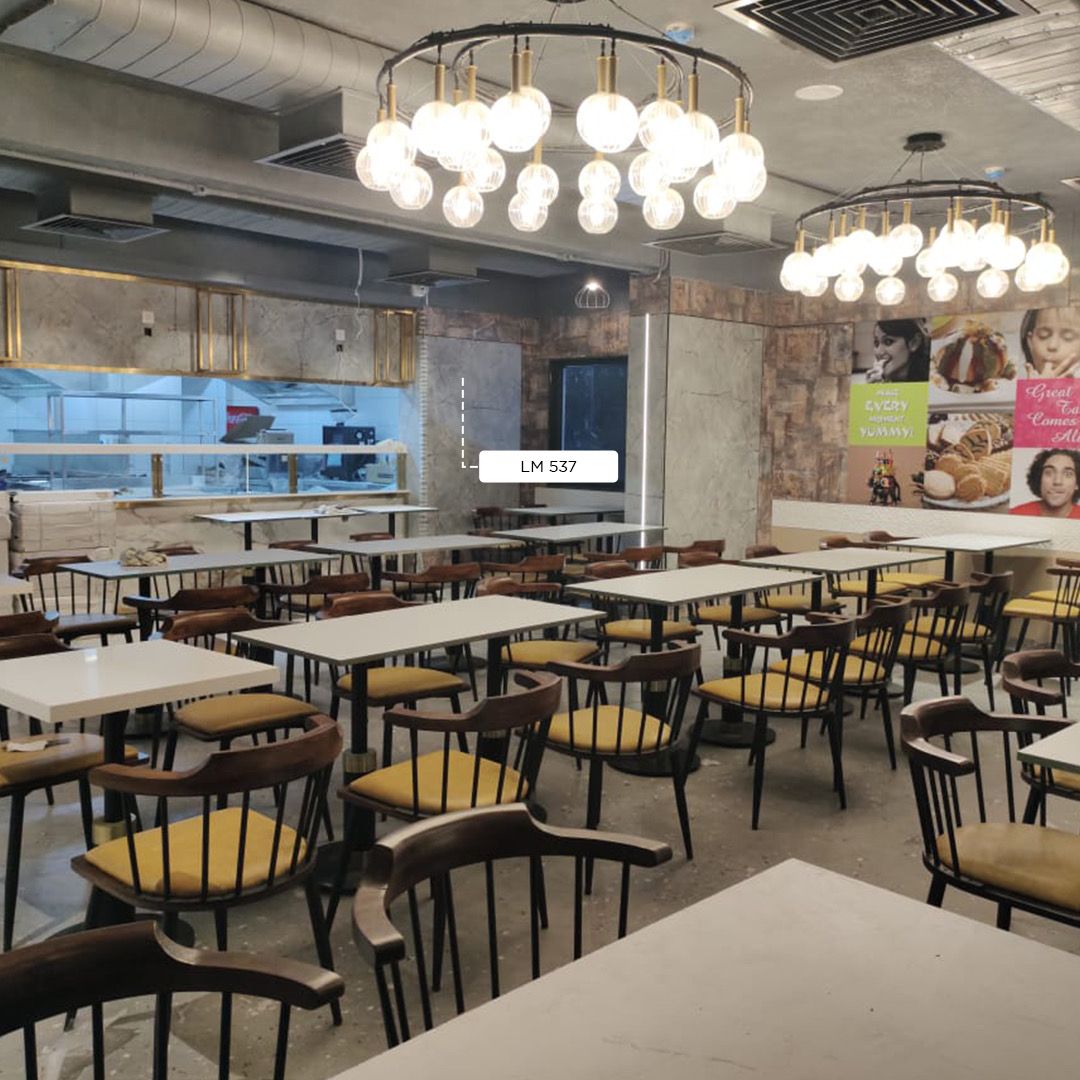 Grey marble laminate wall and counter in a cafe with tables and chairs and large light fixtures above