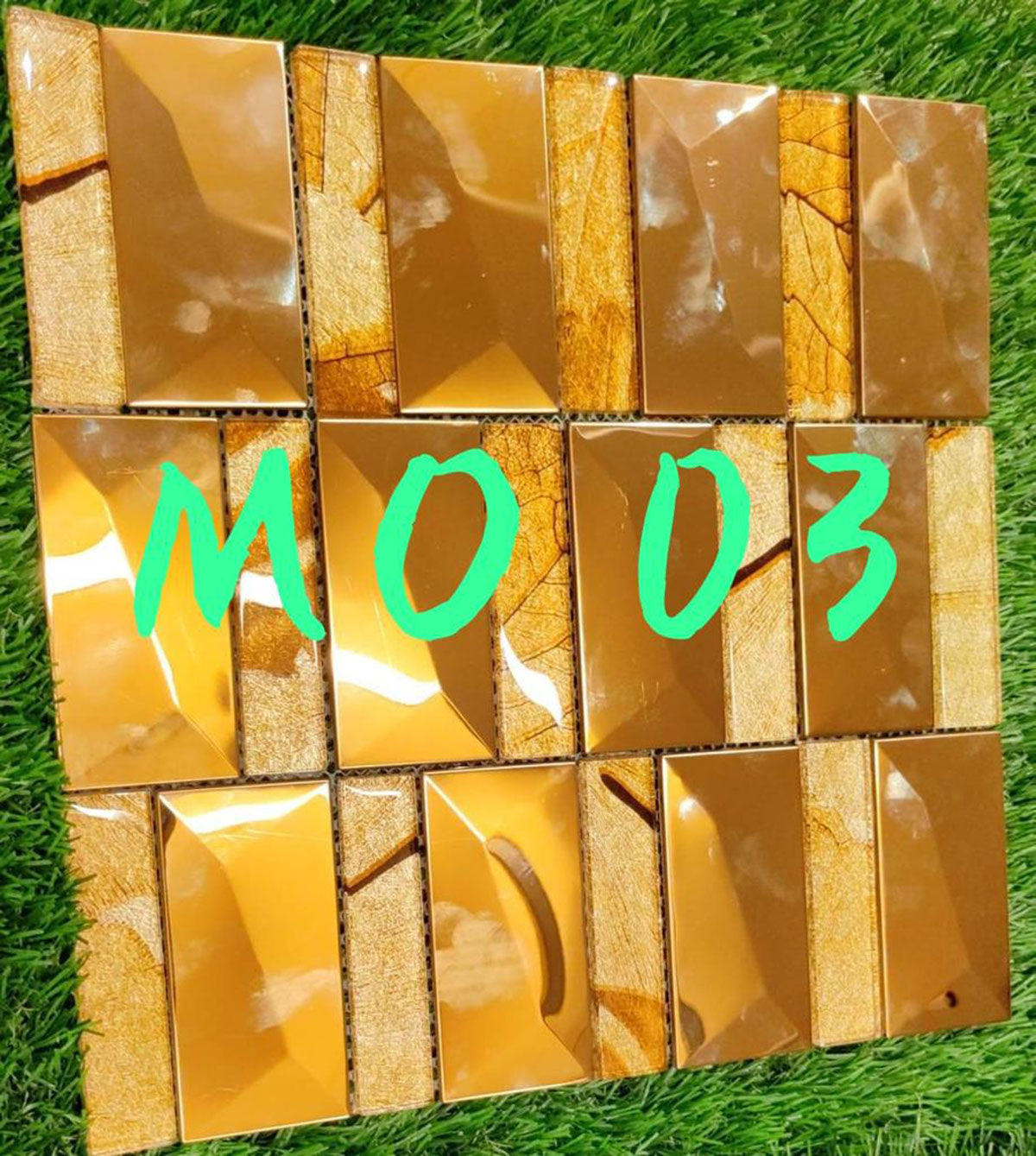 Gold louver wall panel with textured and shiny finish, arranged in grid pattern on green grass background, displaying