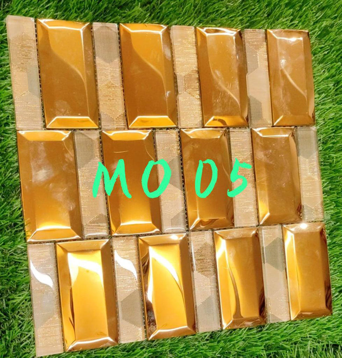 Gold metallic louver panels with textured finish and shiny sheen arranged in grid pattern on green grass background