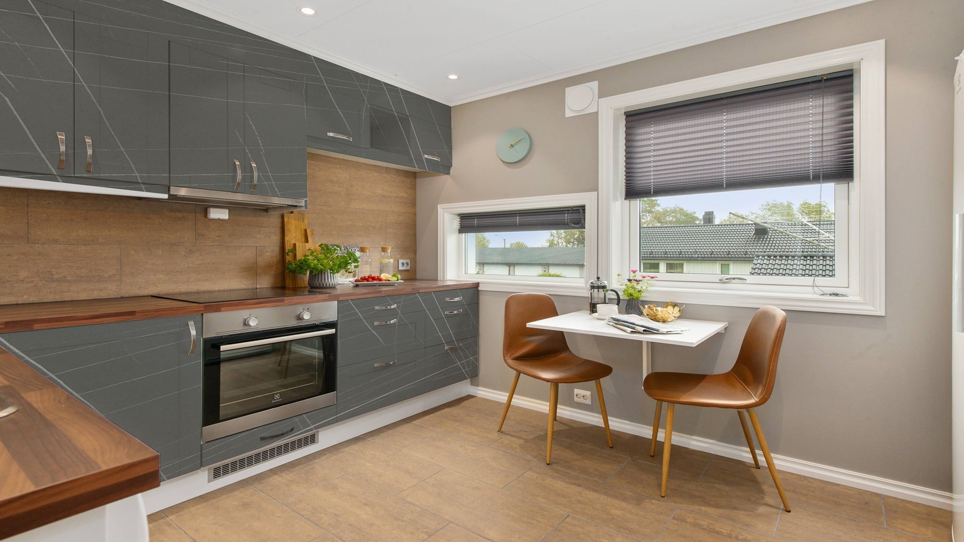 Grey marble laminate kitchen cabinets with matte finish and white veining in a modern kitchen setting with brown chairs.