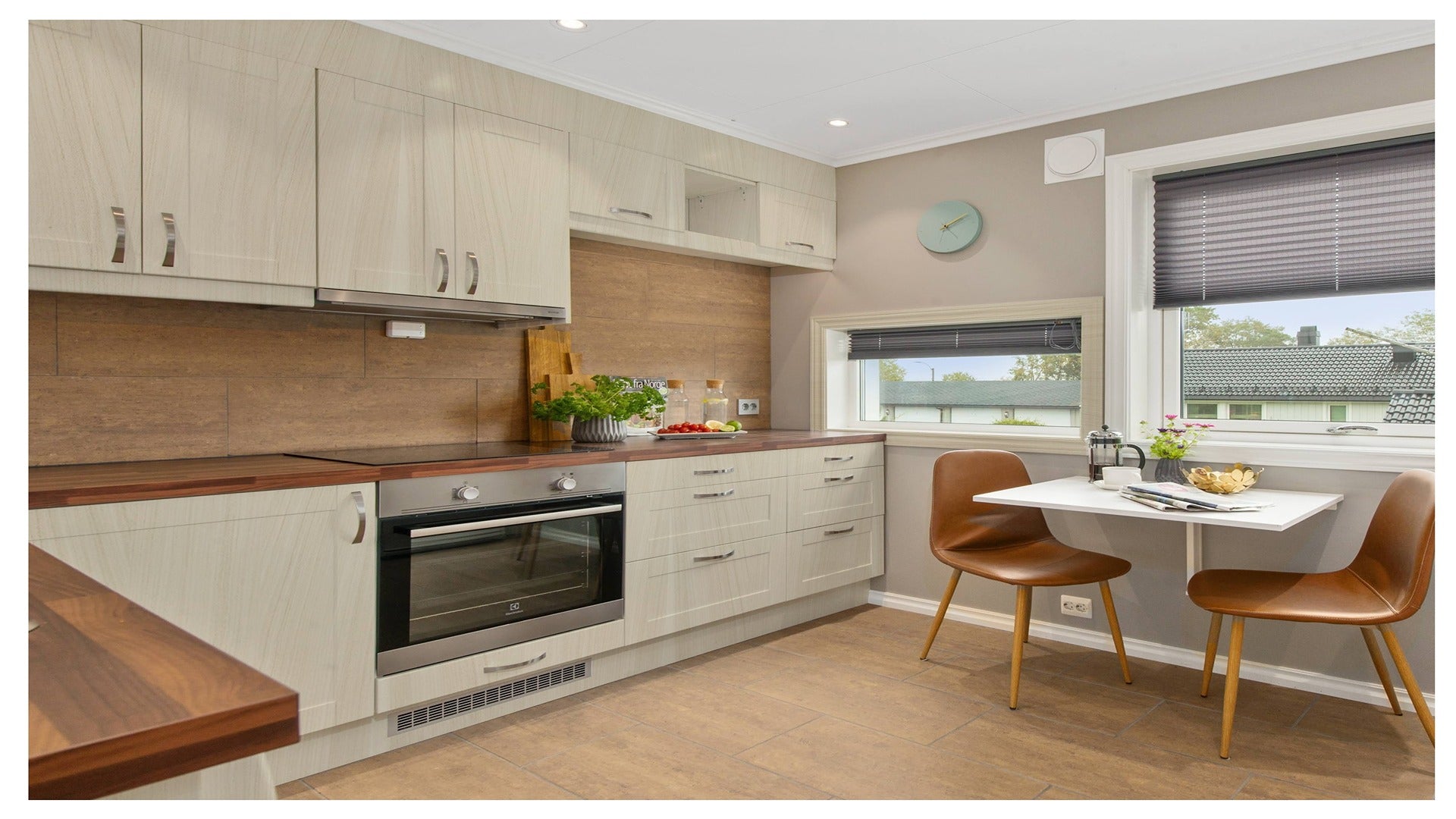 Beige wood grain laminate kitchen cabinets with glossy finish and silver handles in modern kitchen setting with brown chairs