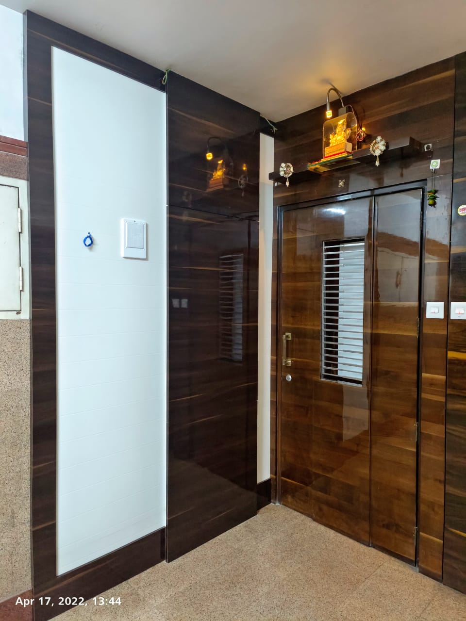 Dark brown wood laminate with glossy finish on wardrobe and wall, showing wood grain texture and reflective sheen.
