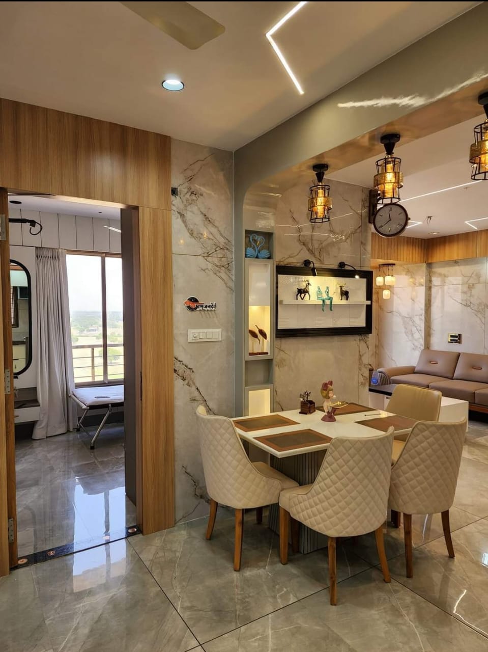 Beige wood laminate wall and brown wood paneling in modern dining room with marble tiles and decorative lighting fixtures