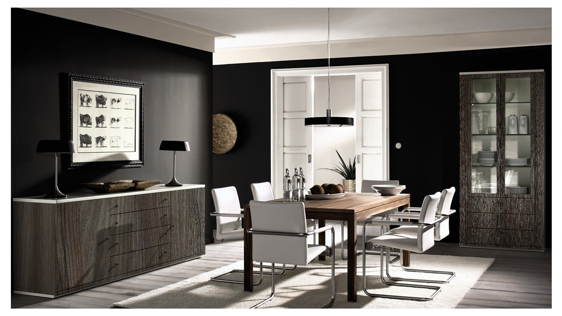 Wood grain laminate furniture in modern dining room with dark walls, white chairs and decorative cabinet and display unit.