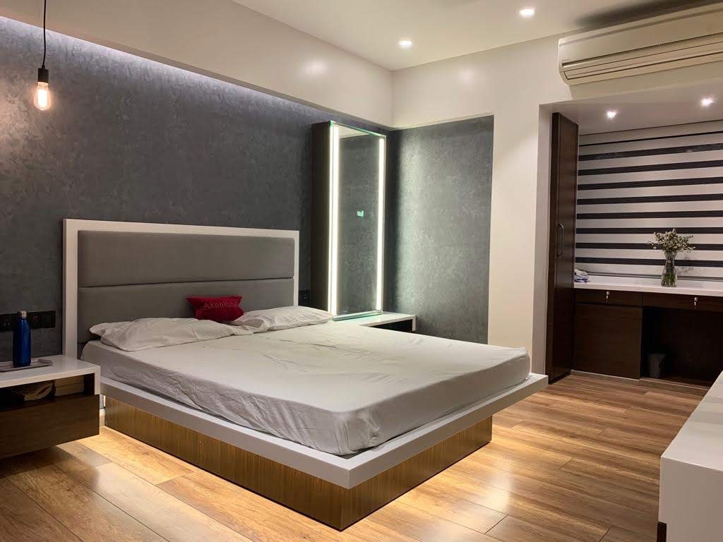 Wood laminate flooring with visible wood grain in modern bedroom setting with bed and furniture
