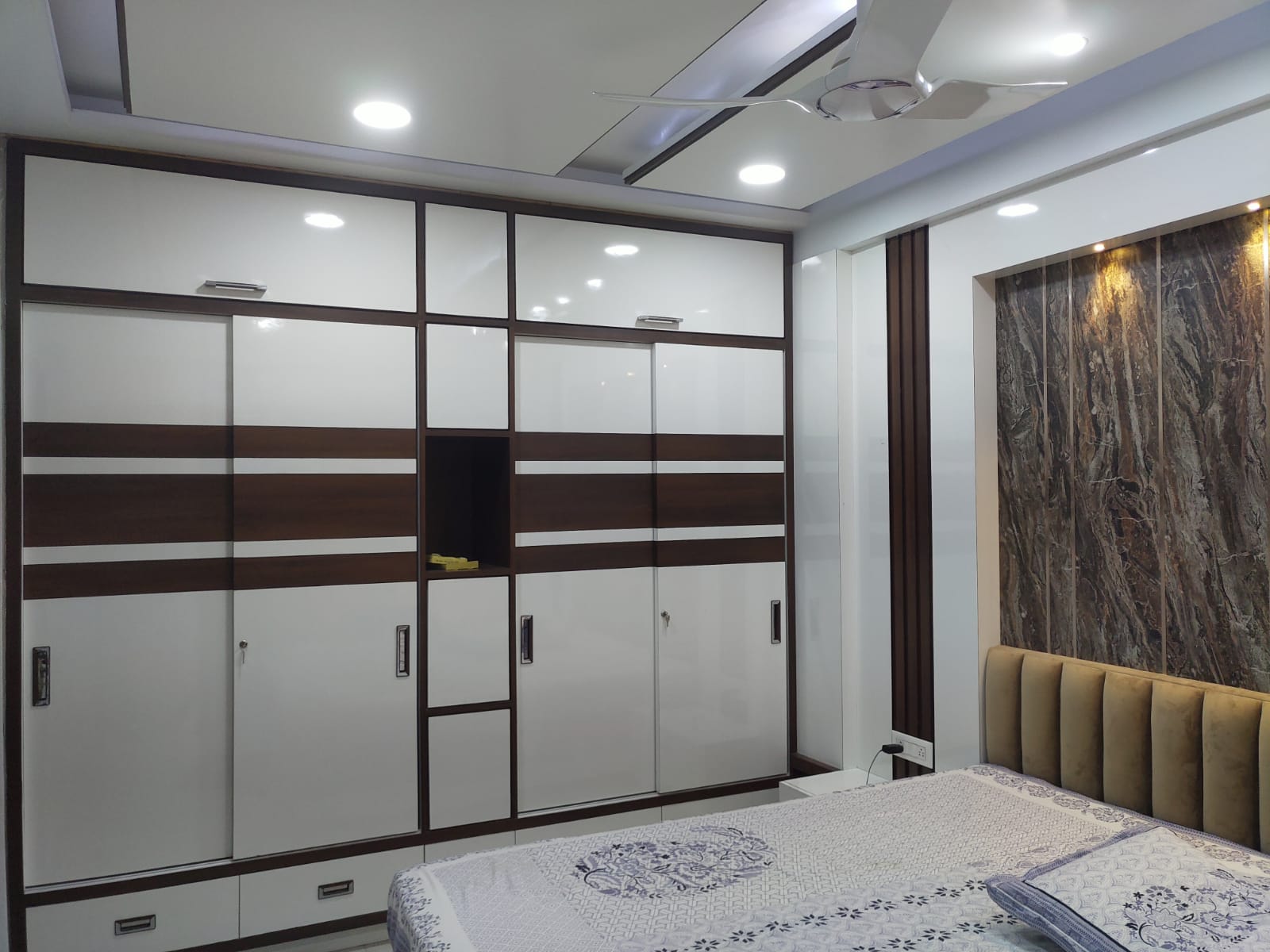 Marble laminate wall panel with dark veining and matte finish in a modern bedroom with white cabinets and brown accents