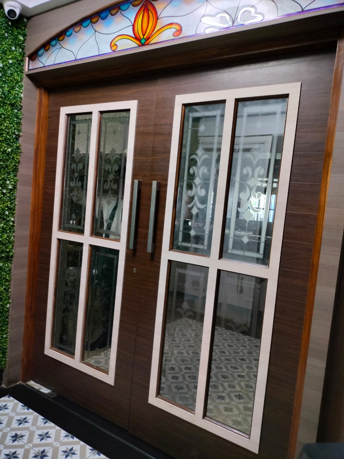 Brown wood grain laminate door with glass panels and silver handles in a modern interior setting