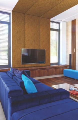 Brown designer louver wall panel with metallic finish installed on a living room wall with blue furniture and wooden floor
