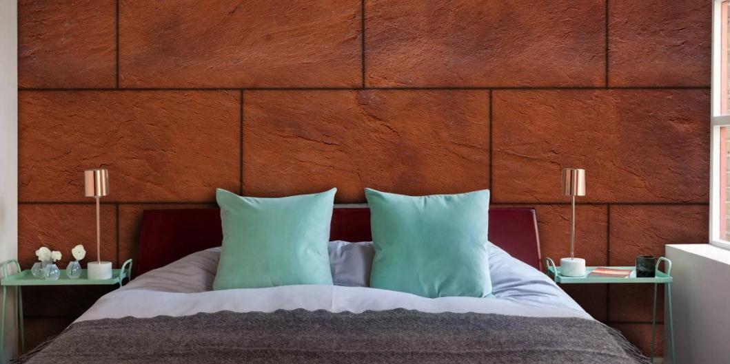 Brown textured wall panel behind a bed with mint green pillows and nightstands with lamps and decorative items